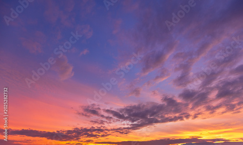 Dramatic Sunset Sky with Vibrant Twilight Clouds,Beautiful twilight sky during sunset featuring a dramatic blend of deep blue and purple clouds illuminated with vibrant orange, pink, and yellow hues.
