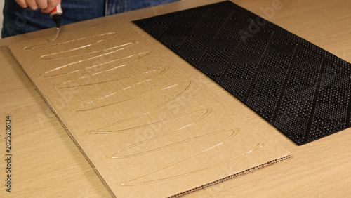 Fotografie Person Applying Liquid Adhesive in Zigzag Pattern to Cardboard Sheet