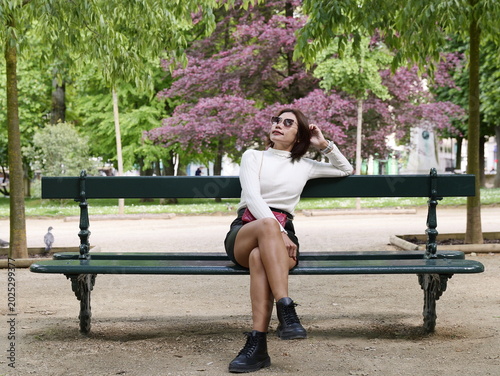 Foto A stylish Asian female model wearing a white turtleneck and black boots sits rel