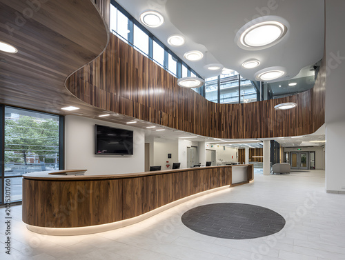 Modern architectural interior showcasing a reception area with curved wooden details, natural light, and a sleek design