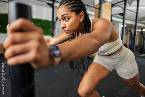 Tablou pe pânză Woman pushing gym equipment showing strength and determination