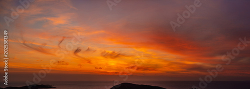 A panoramic view of the dramatic sky during a spectacular sunset over the sea