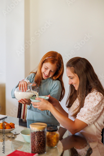 Mother and daughter having breakfast at home in the morning
