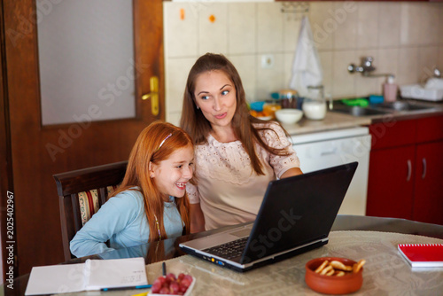 Mother teaching daughter to use laptop computer