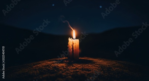 A lone candle burns brightly in the darkness casting a warm glow.