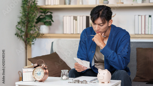 Bilde på lerret Asian man reviewing bills for budgeting, personal finance planning at home