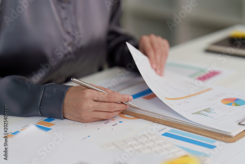 Fotografie Professional reviewing business report with charts and graphs in office