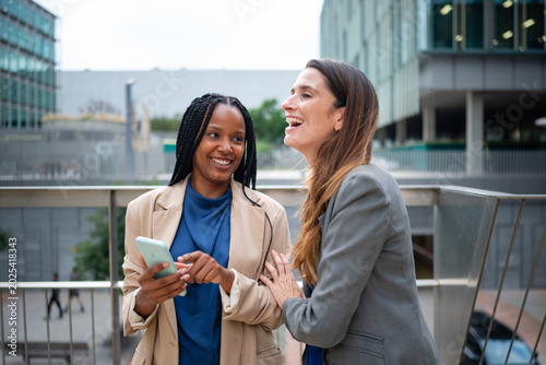 Diverse business women laughing viewing smartphone
