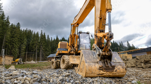 Heavy yellow excavator working on a construction site in a forest clearing