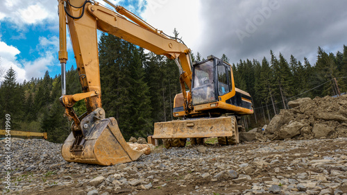 Yellow excavator working on a construction site in a forest clearing