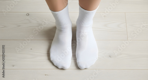 Person standing on wooden floor wearing white socks on feet