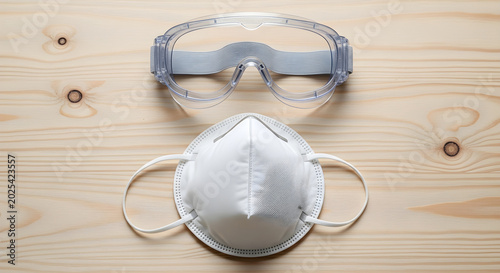 Protective gear including a mask and goggles on a wooden surface