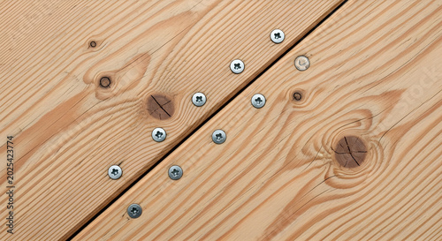 Wooden planks with screws on a wooden surface in an outdoor setting with tools