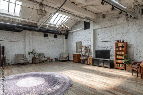 An airy interior with white brick walls, wooden floors, ornate chandeliers, and antique furnishings. Includes seating and bookshelves