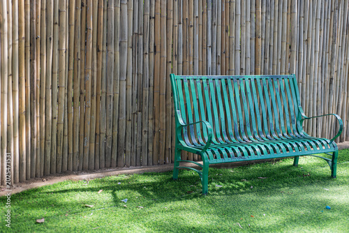 An empty wooden Adirondack chair sits on the green grass of a peaceful garden landscape, offering a relaxing outdoor seat for a summer vacation