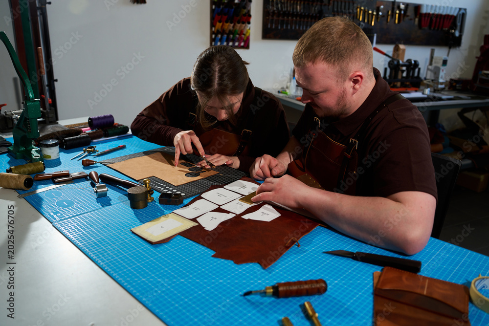 Fototapeta premium Collaborative art workshop with leatherworkers tracing on leather.