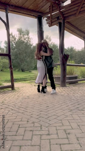 Romantic multiethnic couple dancing bachata in green park. Stylish male and female in close embrace, full length view, summer lifestyle, love and passion outdoors