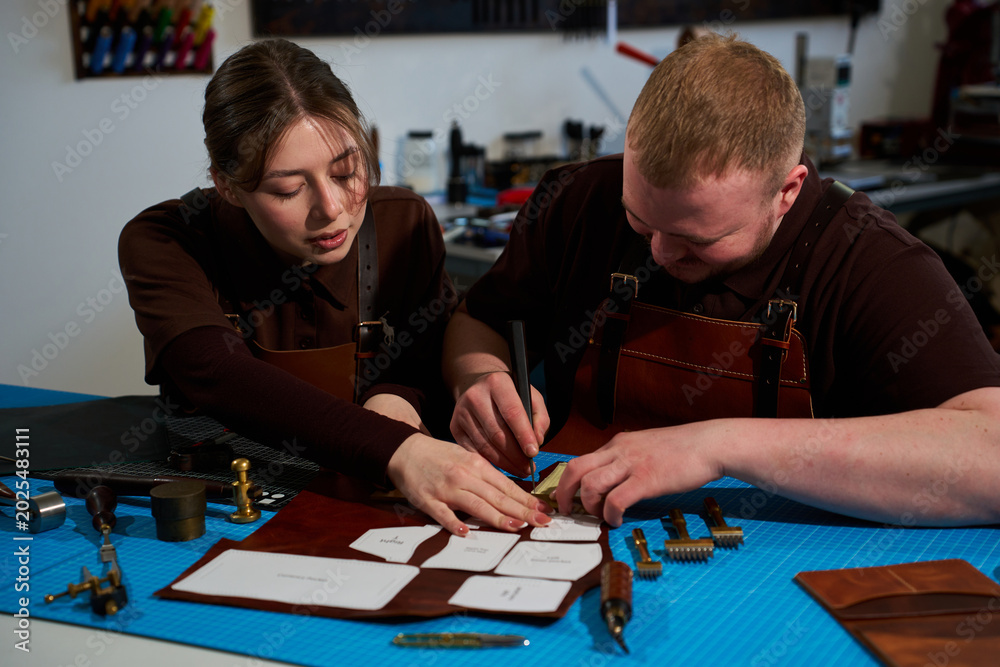 Fototapeta premium Cutting paper patterns on cowhide in a collaborative art workshop.