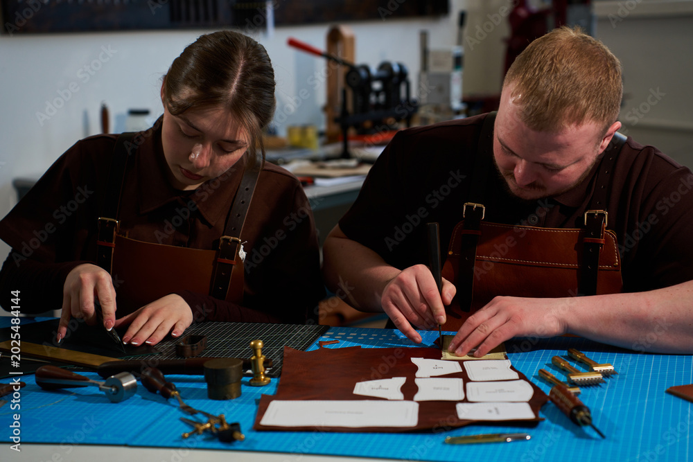 Fototapeta premium Leatherworkers using punches and creasers in a collaborative workshop.