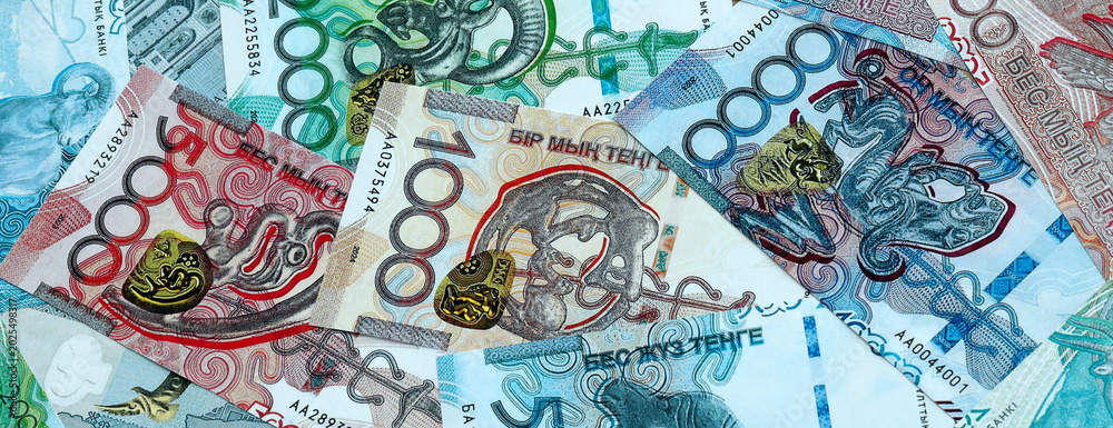 Fototapeta premium Kazakhstani tenge money banknotes pile on table. Kazakhstan bills of KZT currency close up
