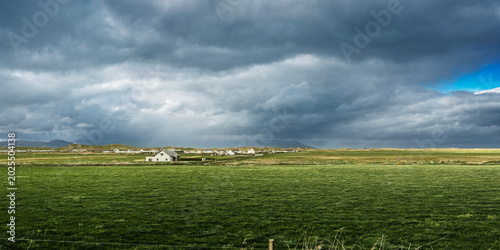 Foto Wide landscape of the Kerry countryside featuring a sunlit pasture and heavy rain clouds at the coast