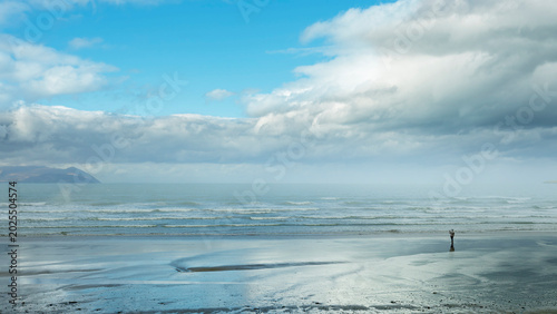 Foto Lone figure walking on the vast reflective sands of Ballyheigue Strand with Dingle Mountains Kerry Ireland