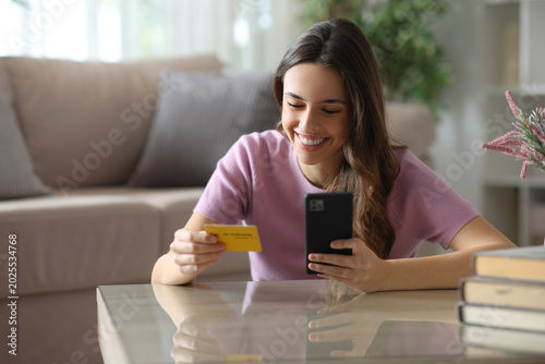 Happy woman paying online on a coffee table