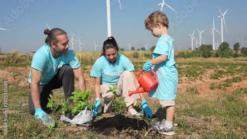 VDO 4K Happy family of father, mother and child are helping each other plant trees on World Warming Day at a wind farm.	