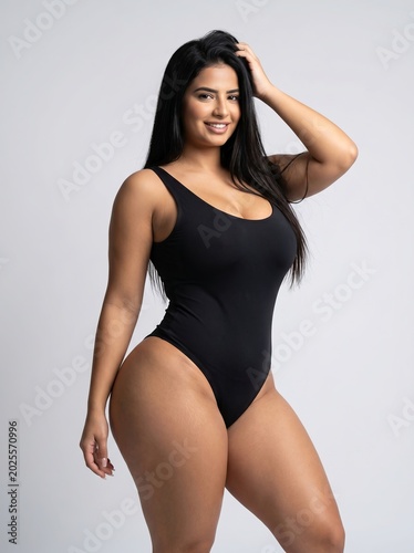 A confident and beautiful young woman, exuding grace and charm in a stylish black swimsuit, captured in a vibrant studio portrait that highlights her radiant smile and elegant posture