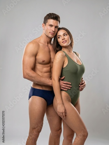 A fit and attractive couple in stylish swimwear posing together in a studio setting, showcasing healthy bodies and a confident, active lifestyle perfect for summer leisure and beach vacations