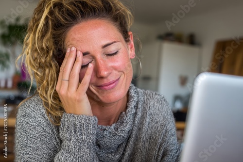 A woman sits at her desk closing her eyes and taking a break to relieve stress from work. She appears focused and at ease while resting