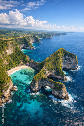 “Aerial view of limestone cliffs, turquoise waters, sandy beaches, and lush greenery along a tropical coastline captured from above