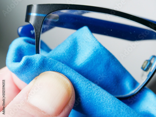 Принти на полотні Close-up of a hand cleaning eyeglasses with a blue microfiber cloth