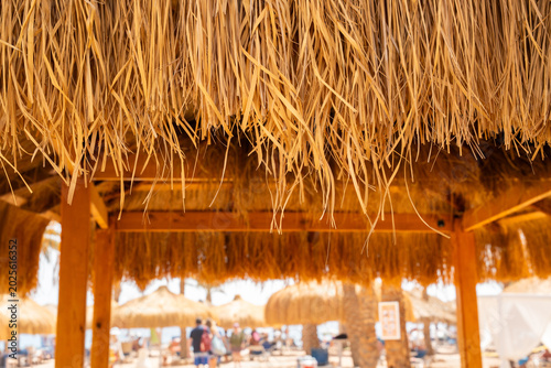 Close view of straw roof at beach resort in Sharm El Sheikh Egypt with Red Sea vacation area in soft focus. Travel and resort lifestyle