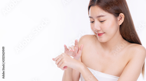 Photos Beautiful young Asian woman with flawless skin applying moisturizing lotion on her hand against an isolated white background