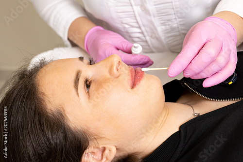 Tableau sur toile A picture of a very beautiful and attractive young lady showing the process of lip injection and rejuvenation, in a professionally arranged office
