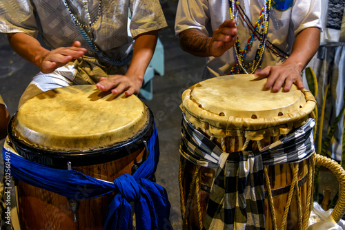 Drummers playing a traditional atabaque drum decorated with cloths during an Umbanda celebration in Brazil.