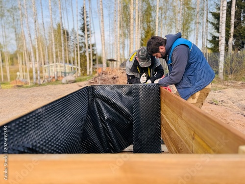 Foto Men construct a tall raised garden bed from larch wood and line the inside with