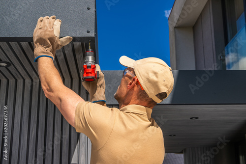 Konstfotografi Worker installs fixture on modern building in daytime hours