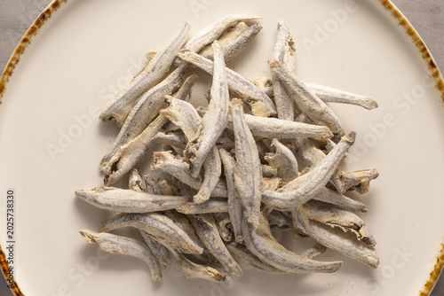 Vászonkép Small dried anchovies on plate, rustic pantry food and drink scene, silvery snac