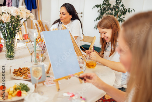 Photos Group of women engaged in creative painting activity at a bright studio, with ea