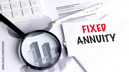 Fixed annuity concept with magnifier calculator pen and financial charts on desk guaranteed income 