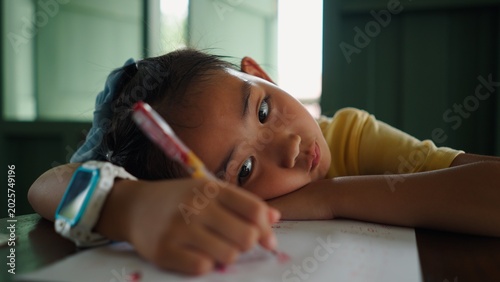 Obraz na plátně Young asian girl looking bored and tired while doing homework or studying at hom