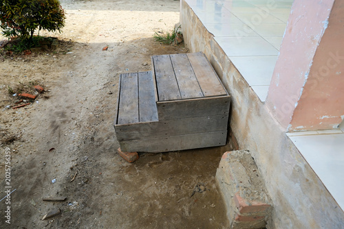 Konstfotografi Weathered two-step wooden staircase placed outdoors on a dirt ground next to a tiled porch building base