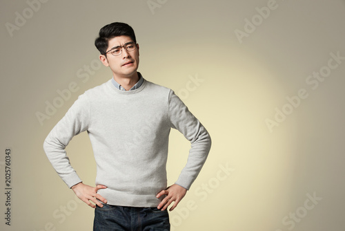 Tableau sur toile Skeptical young man with hands on hips