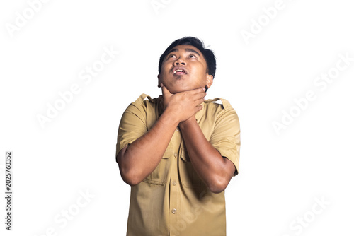 Φωτογραφία Panicked young man in a khaki uniform shirt clutching his neck with both hands in a choking gesture while looking upward with open mouth against a white background