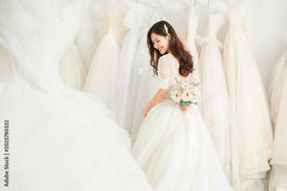 Fototapeta premium Smiling bride holding bouquet in bridal boutique
