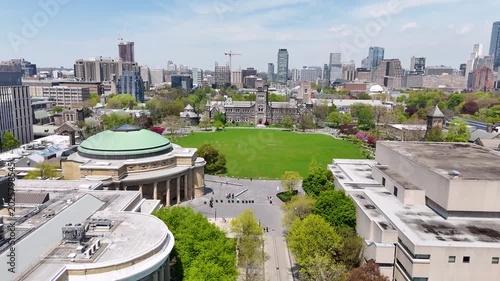 Aerial view flying forward over King's College Circle toward the historic romanesque revival facade of University College in Toronto