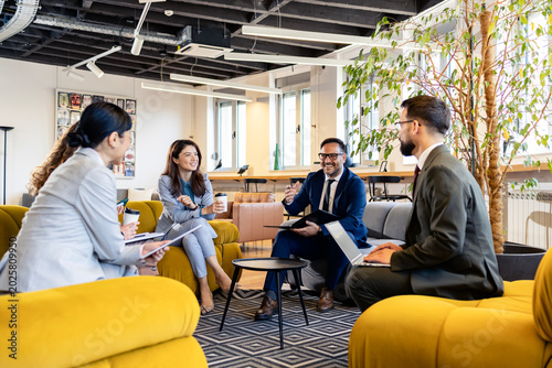 Business team collaborating in a modern office lounge, discussing strategies and ideas with diverse coworkers in a relaxed setting