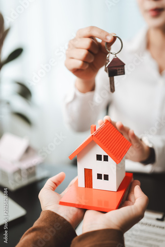 Real estate agent giving keys to new home owner, representing successful property acquisition, buying, investment, and profitable residential transaction
